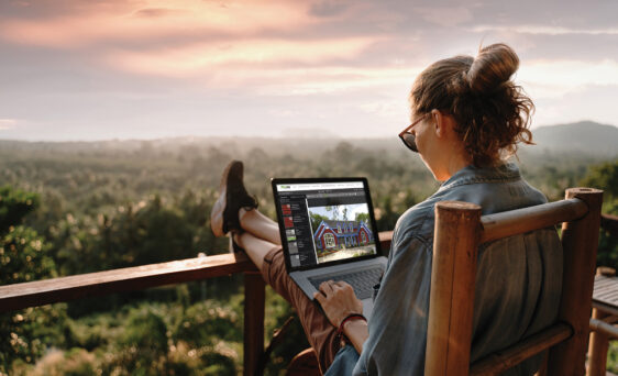 {Woman on a laptop outside using ProVia's Design Center home exterior design tools to design home exterior solutions.}