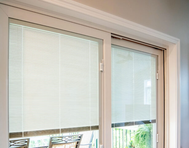 {Closeup image of white blinds in sliding glass doors, which are ProVia Endure vinyl sliding glass patio doors}