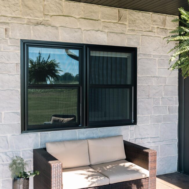 {Endure Double Hung windows with clear glass in Coal Black against a white stone home exterior}