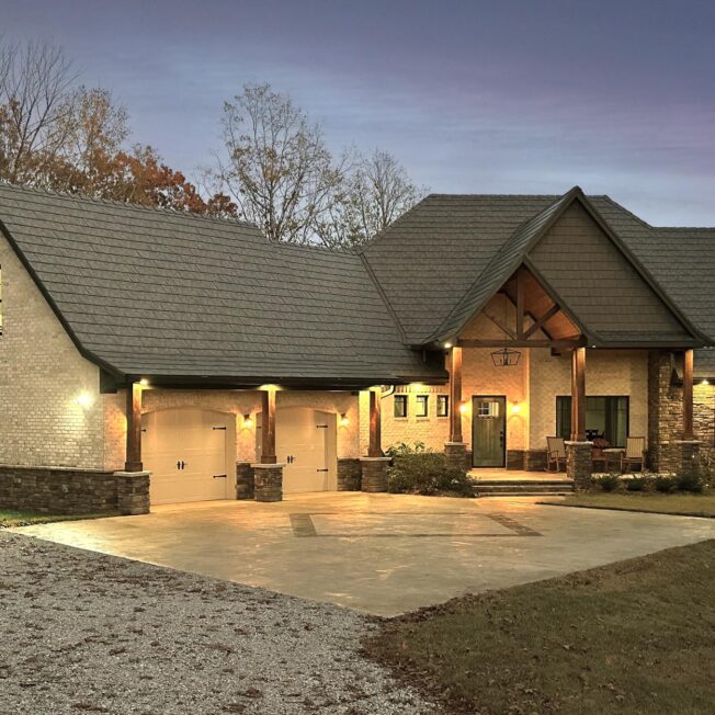 {Photo of a home at dusk with ProVia's Larkstone Slate metal roofing and Shawnee Dry Stack stone}