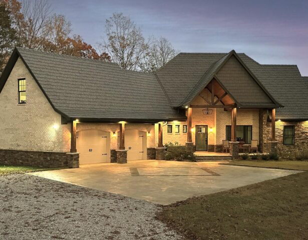 Photo of a home at dusk with ProVia's Larkstone Slate metal roofing and Shawnee Dry Stack stone