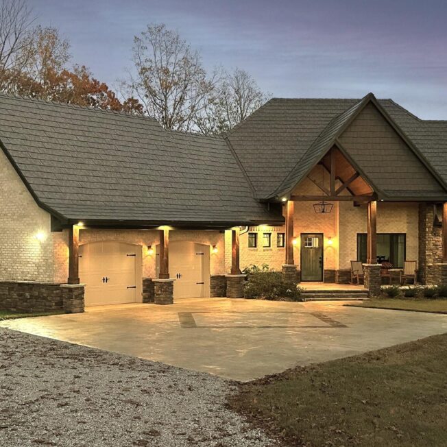 Photo of a home at dusk with ProVia's Larkstone Slate metal roofing and Shawnee Dry Stack stone