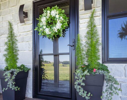 {Spectrum Full View glass storm door in Coal Black over a Signet fiberglass entry door, which contrasts nicely with white stone on a home exterior}