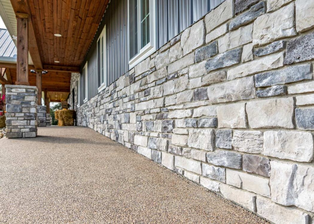 {Terra Cut Frost manufactured stone veneer on the bottom portion of a home's exterior, example of stone colors that combine grays, whites, browns, and a hint of reds}