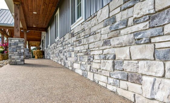 {Terra Cut Frost manufactured stone veneer on the bottom portion of a home's exterior, example of stone colors that combine grays, whites, browns, and a hint of reds}