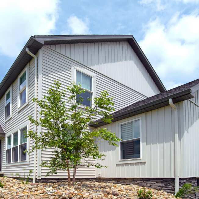 {Colonial-style house with Cedar Peaks 8" board and batten siding in White}