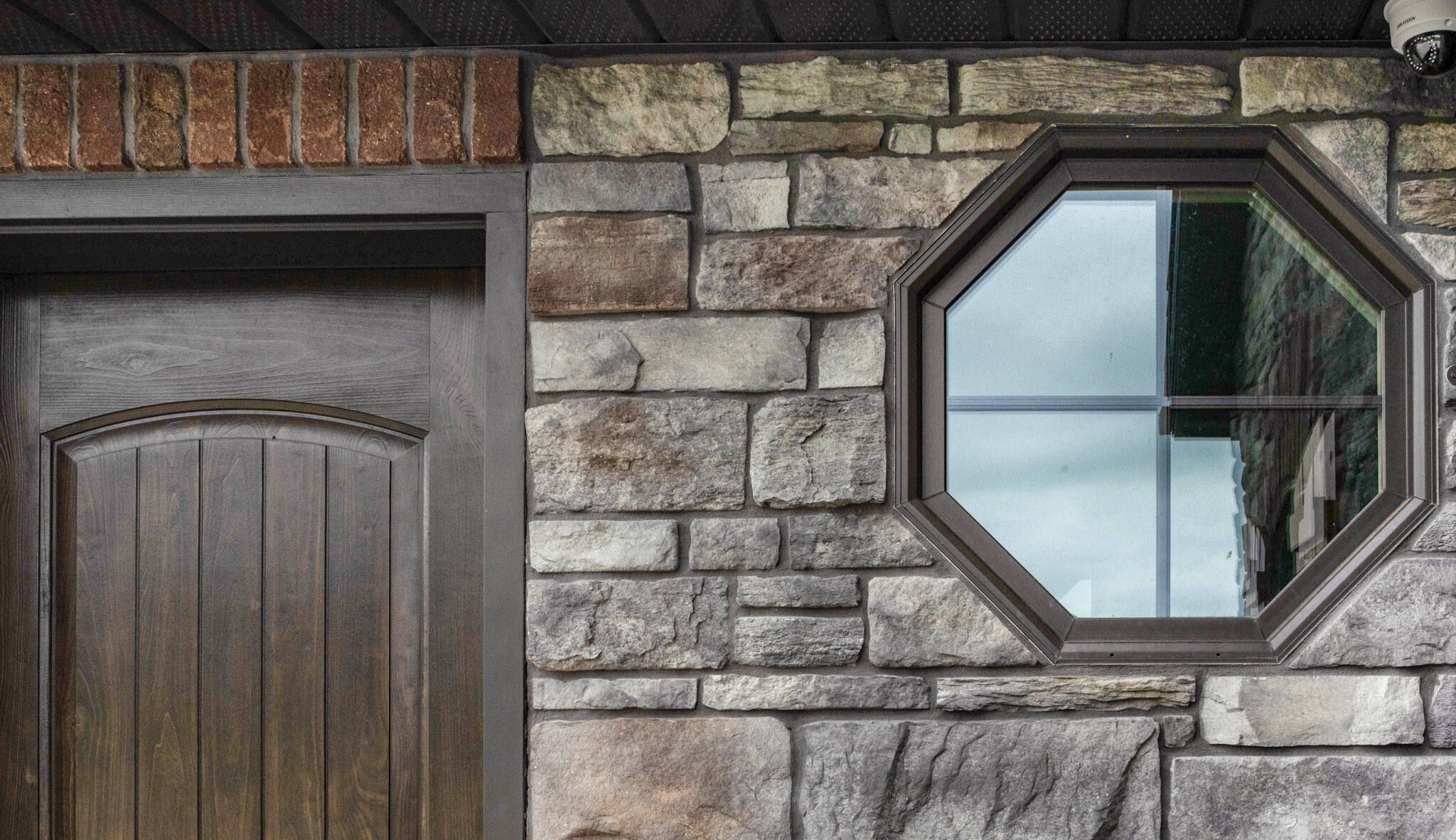 Stone home exterior with octagon windows with Rustic Bronze finish; example of shaped custom home windows in ProVia's window gallery
