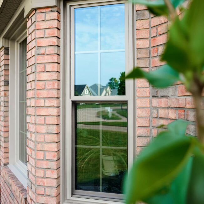 {Outside view of Aeris™ Double Hung Windows in Sandstone with Colonial Grids on a brick home}