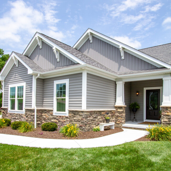 {House with ProVia vinyl siding HeartTech double 5" in Granite with a manufactured stone knee wall}