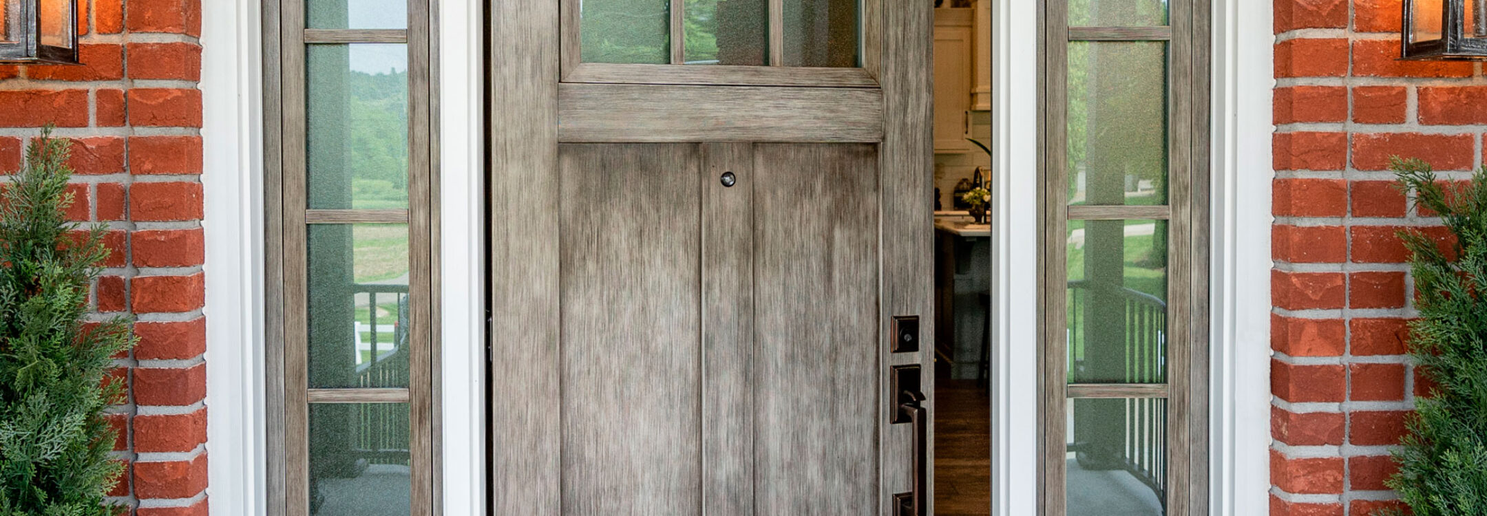 {Signet fiberglass fir door and sidelites in Natural Leather gray glaze on the porch of a red brick home}