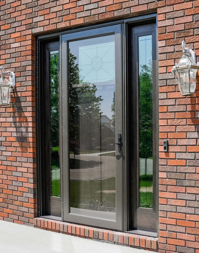 {Outside view of a red brick home with a Deluxe Full View storm door in Tudor Brown}