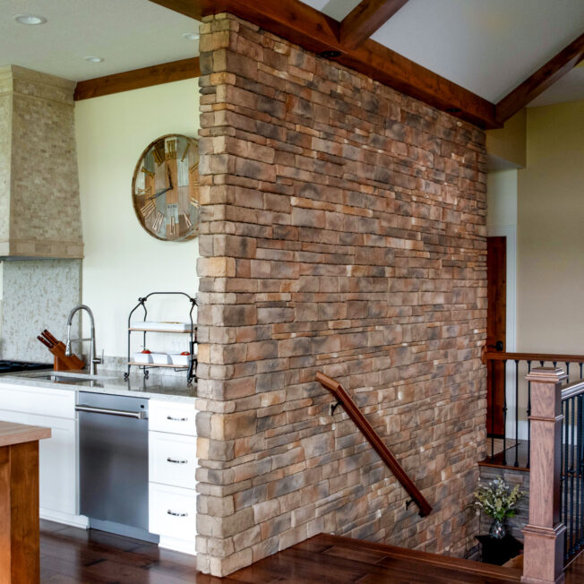 {Photo of a feature stone interior wall with ProVia's Dry Stack stone in the color Colorado, which includes a mix of brown, red, and gray stone}