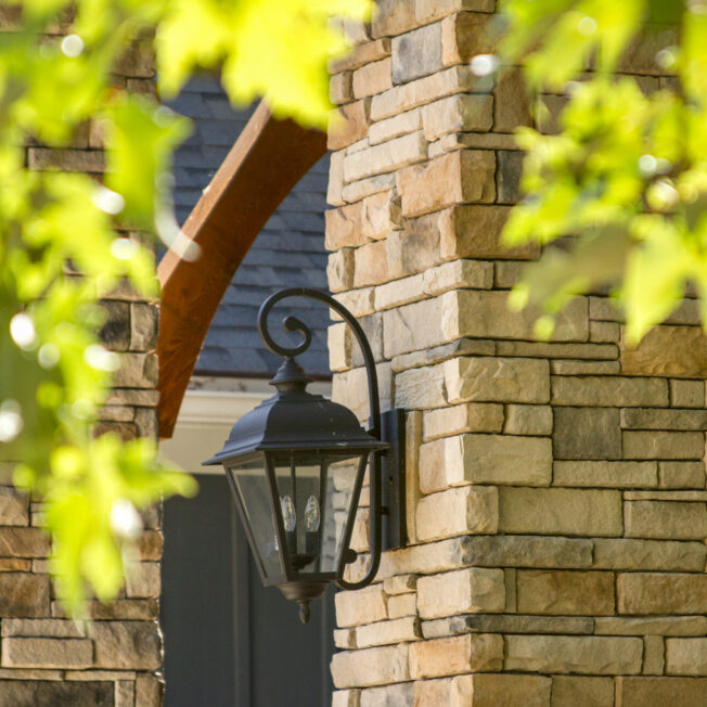 {Closeup of a home exterior with dry stack stone veneer in a color called Seneca, home exterior color ideas for brown stacked stone}