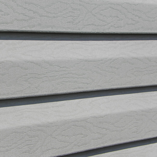 {Closeup of HeartTech® Dutch Lap Vinyl Siding in Gray showing the unique oak woodgrain texture}