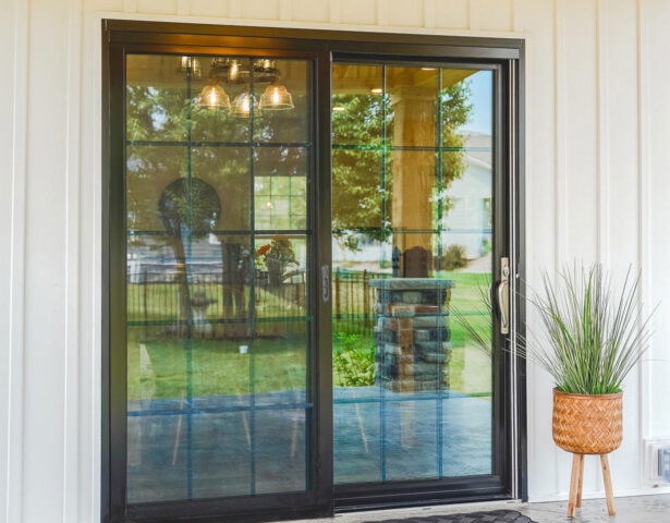 Exterior view of a ProVia Endure™ Patio Door in Black with Colonial Grids on a house with white siding