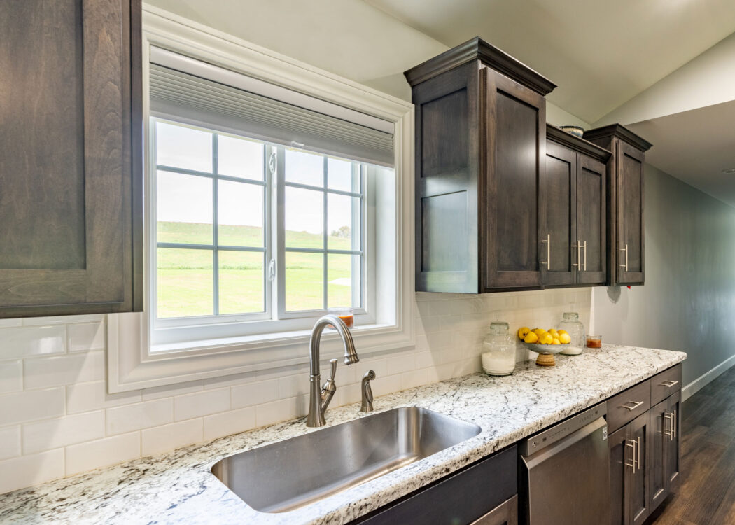 {White sliding windows with cottage-style grids in a kitchen above the sink; example of slider pictures of windows in ProVia's window gallery}