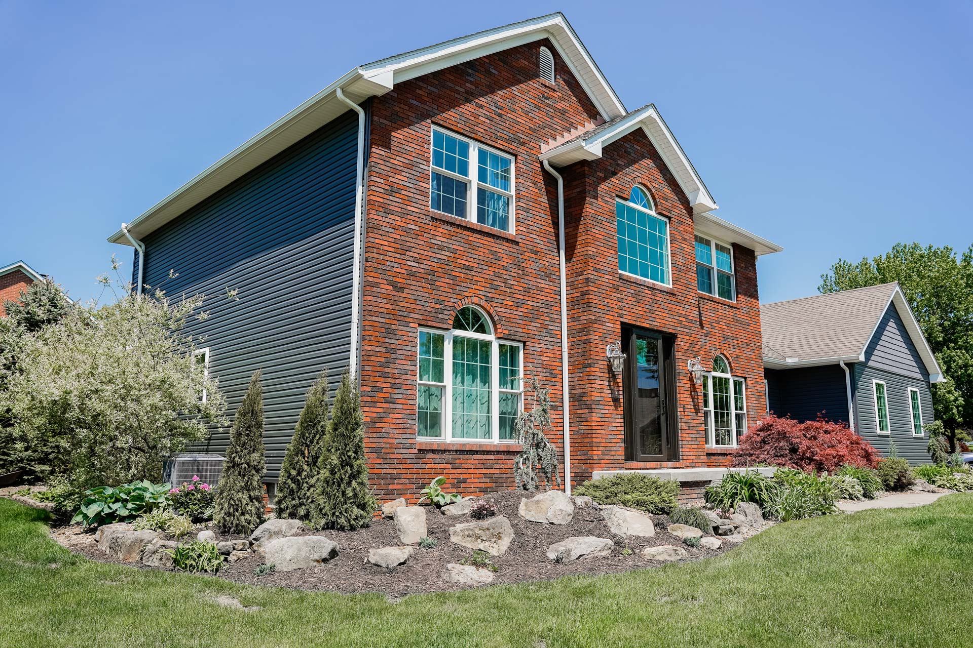 {Brick two-story home with HeartTech® Vinyl Siding in Sea Slate and Endure™ Windows in White}