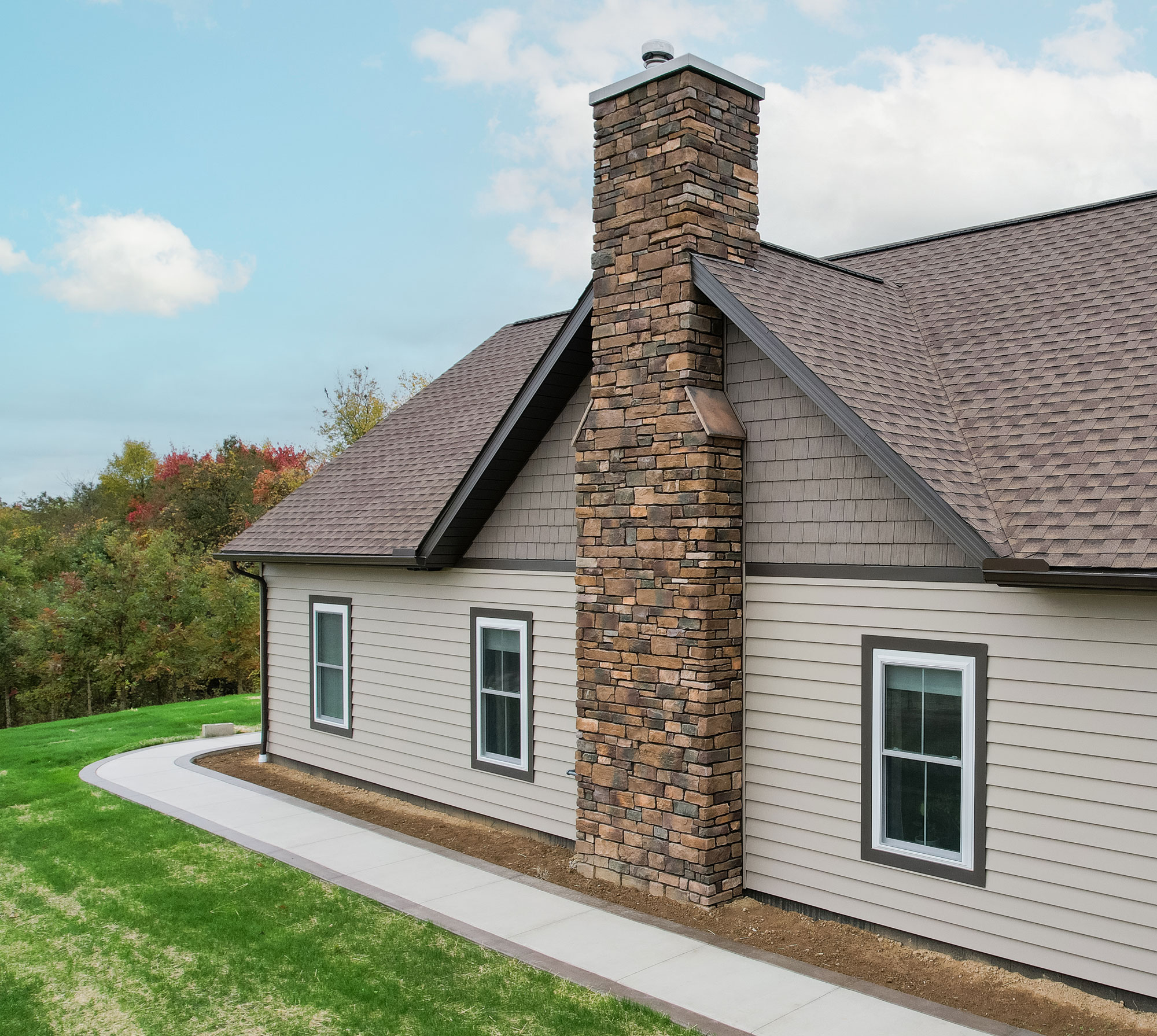 Aerial view of ProVia Harbor Mill™ Shake in Pueblo and CedarMAX® D6 Vinyl Siding in Clay on the side of a home with a chimney