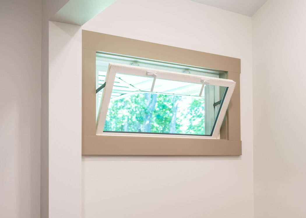{An opened Sandstone colored hopper window in a laundry room}