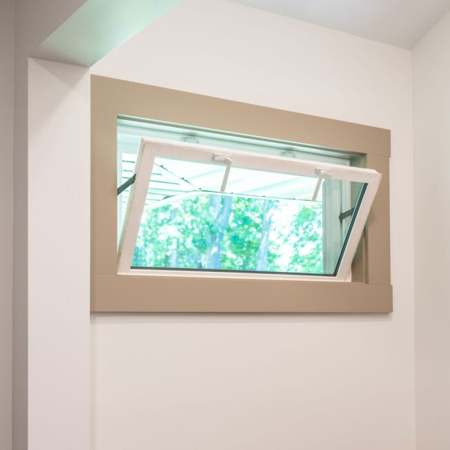 {An opened Sandstone colored hopper window in a laundry room}