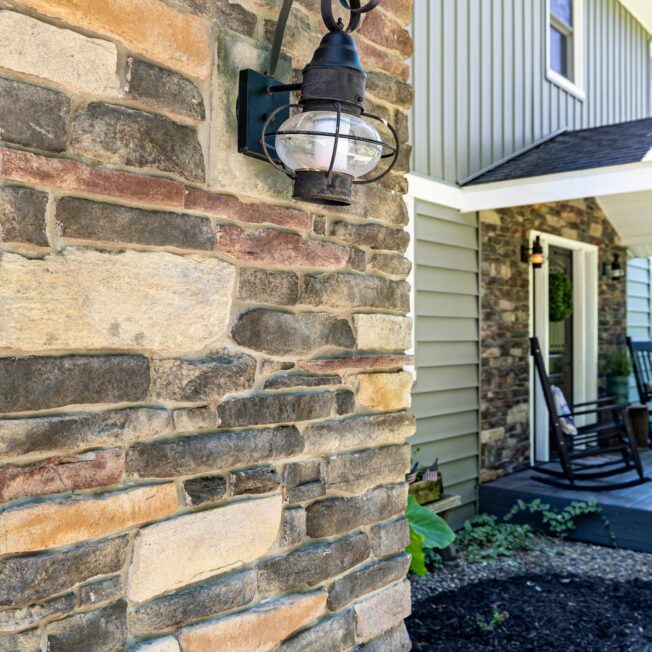 {Closeup view of Ledgestone veneer in the color Saginaw, which includes a blend of browns, grays, and reds on a home exterior}