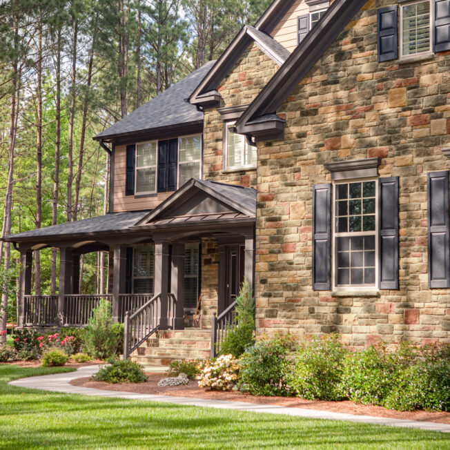 {ProVia Limestone manufactured stone veneer in the color Allegheny on the exterior of a two-story home}