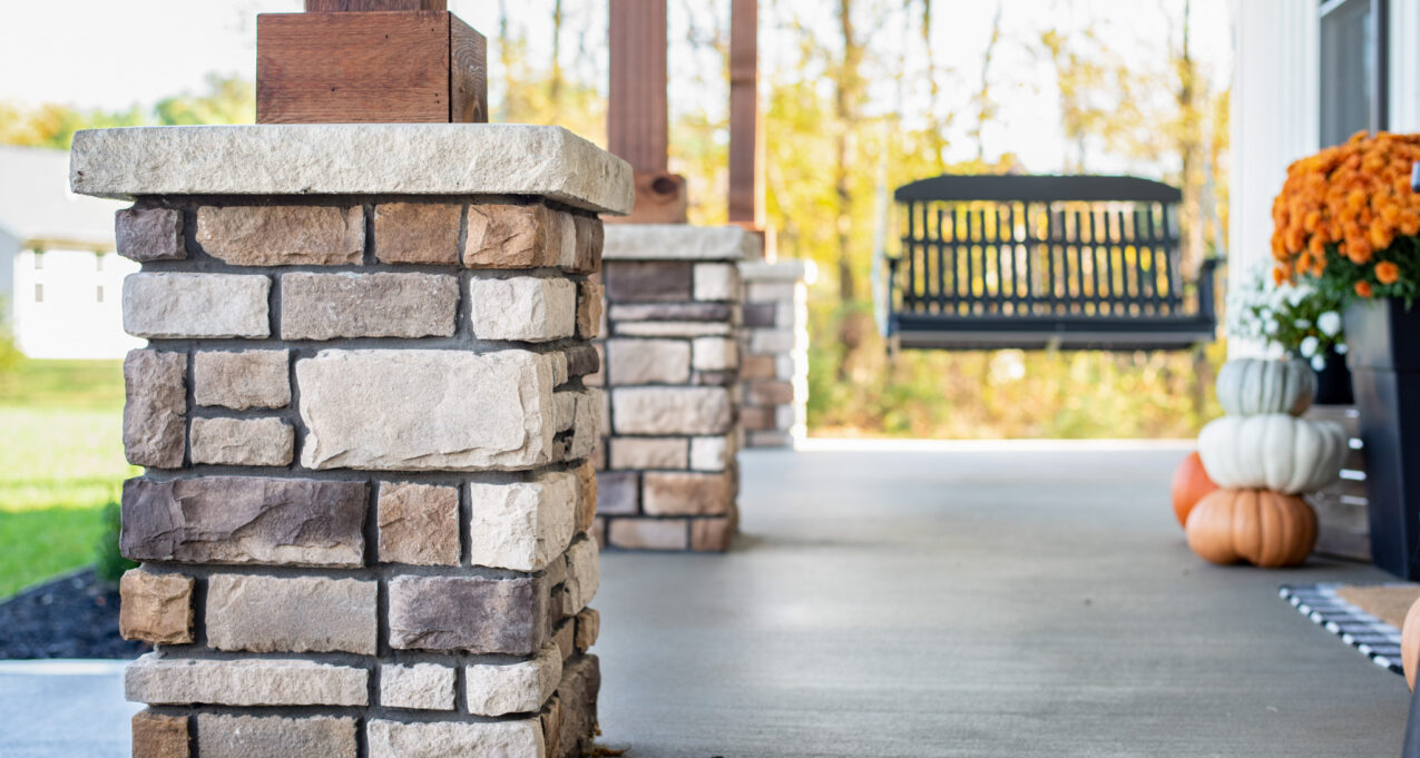 Limestone veneer manufactured stone columns on a porch in the color Amherst, dark grout shows an example of how to choose grout color that complements your stone color
