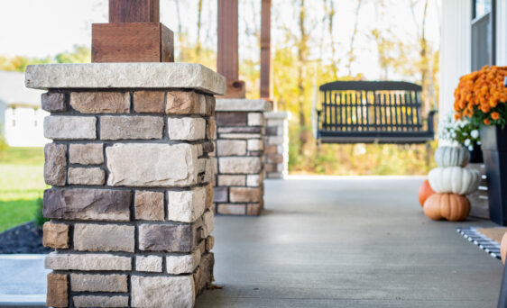 {Limestone veneer manufactured stone columns on a porch in the color Amherst, dark grout shows an example of how to choose grout color that complements your stone color}