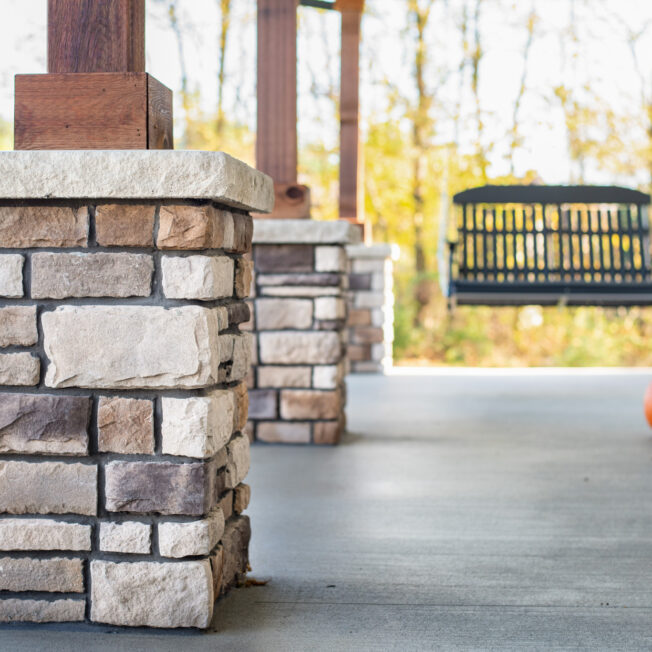 {Limestone veneer manufactured stone columns on a porch in the color Amherst, dark grout shows an example of how to choose grout color that complements your stone color}