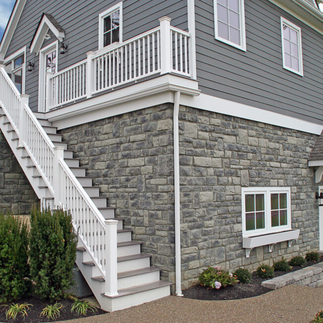 {ProVia Limestone Blue Ridge manufactured stone on the exterior bottom half of a home with a walkout basement}