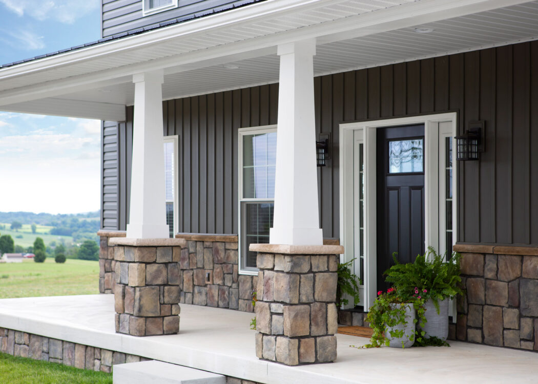 {View of ProVia's Natural Cut manufactured stone veneer in Ashworth, example of how ProVia stone can be combined with stone veneer accessories and applied to porch columns and on the exterior of a home}