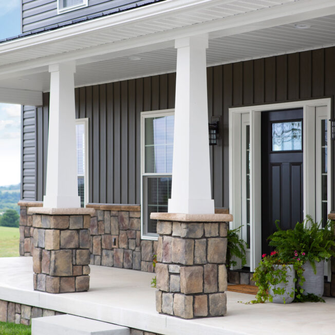 {View of ProVia's Natural Cut manufactured stone veneer in Ashworth, example of how ProVia stone can be combined with stone veneer accessories and applied to porch columns and on the exterior of a home}