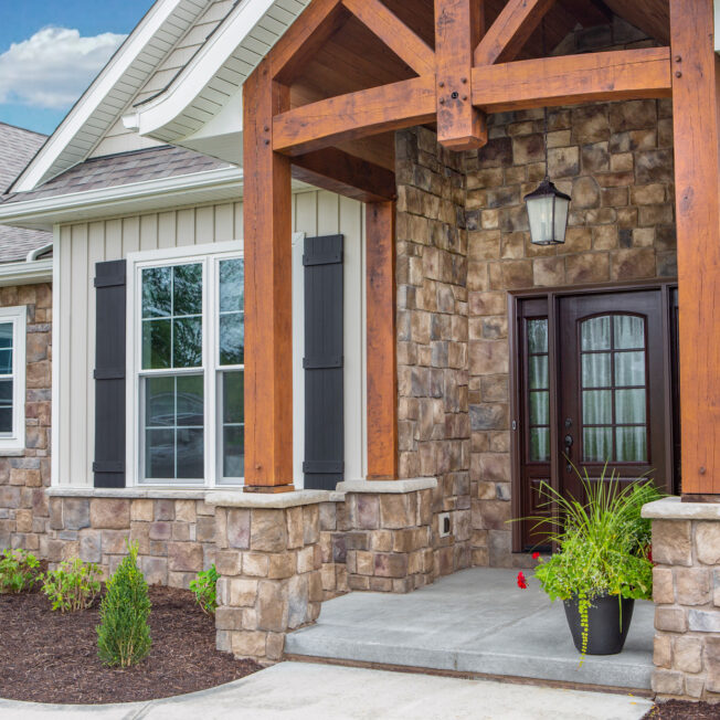 {ProVia Natural Cut™ Woodbridge Manufactured Stone on the exterior of a craftsman-style home paired with siding and timber framing}