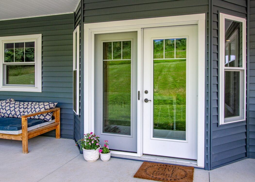 {Home with dark blue vinyl siding and a white hinged patio door}