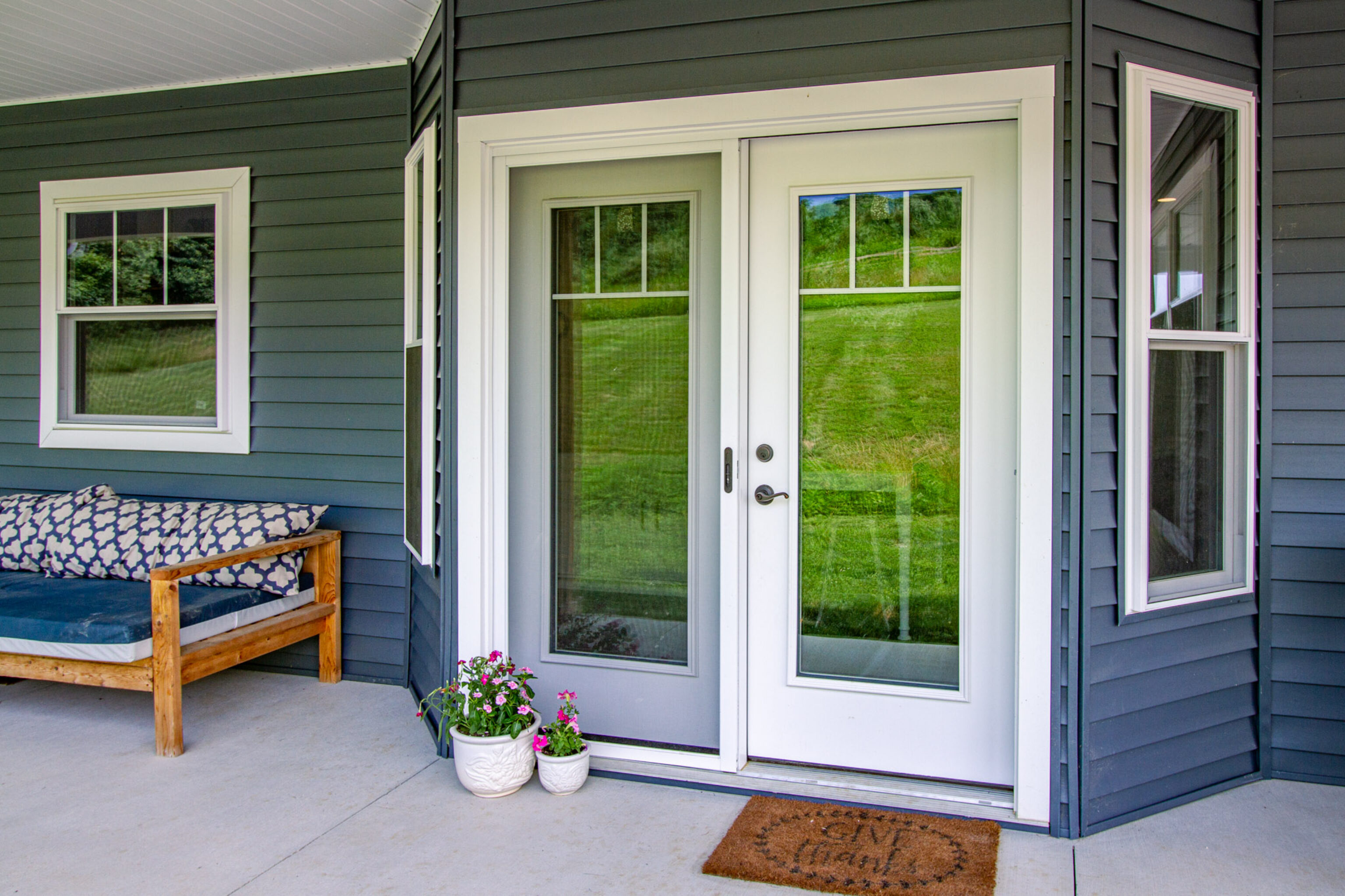 {Home with dark blue vinyl siding and a white hinged patio door}