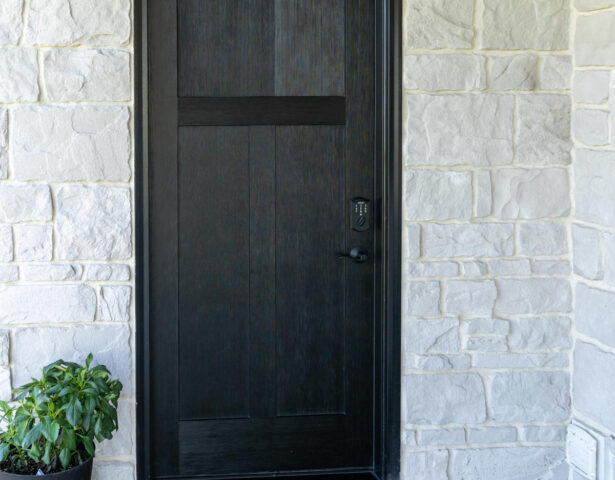Signet fiberglass front door with Fir skin and Coal Black paint, which contrasts nicely against white stone
