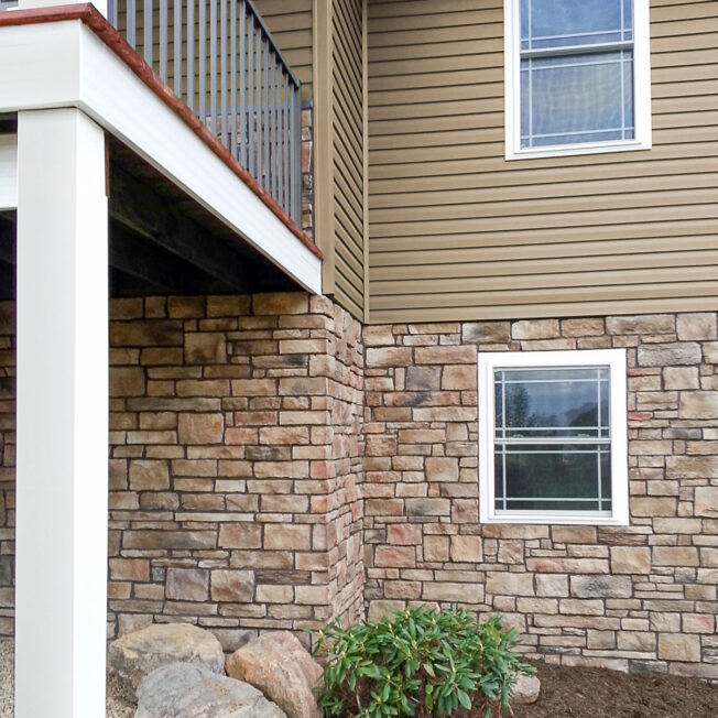 {ProVia Terra Cut manufactured stone on the lower level of a home in the color Russet, example of how exterior stone for houses can be used}