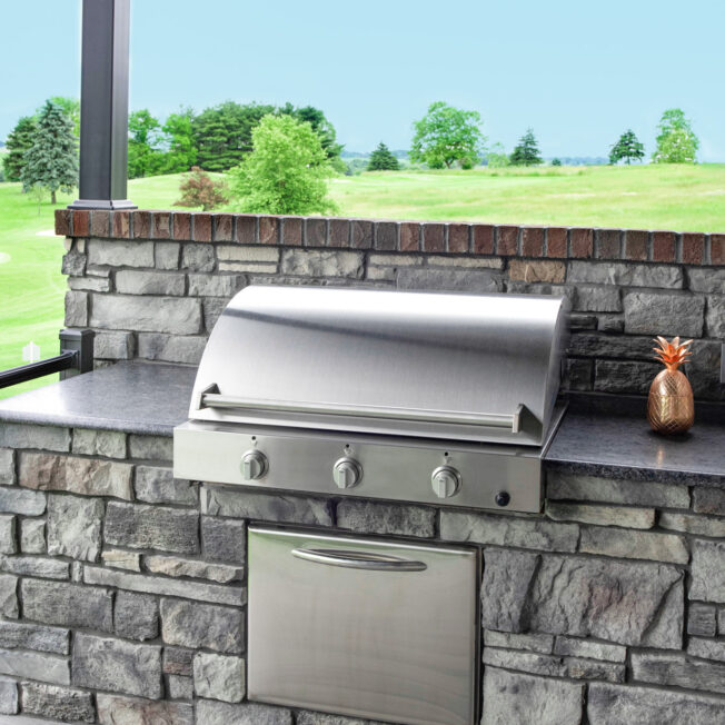 {Outdoor kitchen grill area featuring ProVia's Terra Cut manufactured stone in the color Slate in ProVia's stone gallery}