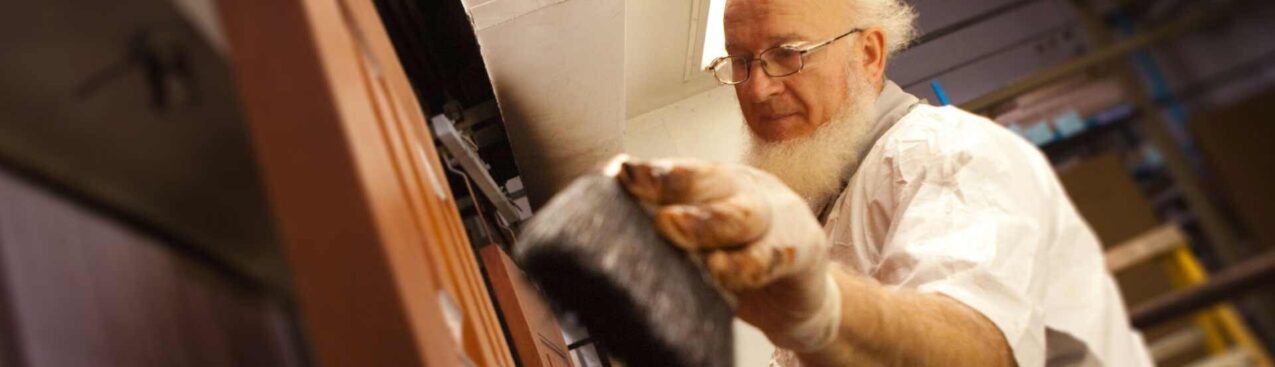 {Amish employee applying stain to a door, example of factory applied door colors, painted exterior doors, and exterior door stains}