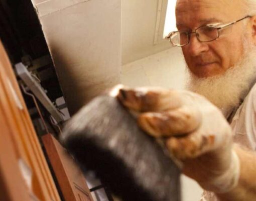 {Amish employee applying stain to a door, example of factory applied door colors, painted exterior doors, and exterior door stains}