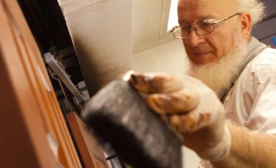 {Amish employee applying stain to a door, example of factory applied door colors, painted exterior doors, and exterior door stains}