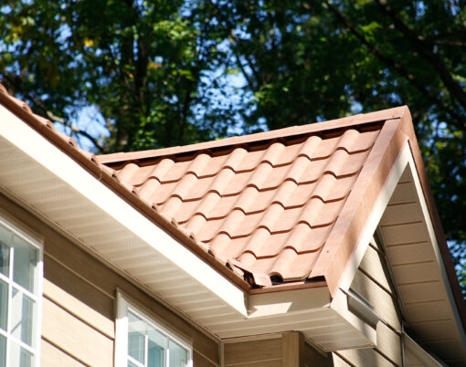 {Closeup view of a home with ProVia's new metal barrel tile roof in Terracotta, example of metal roofing that looks like clay tile}