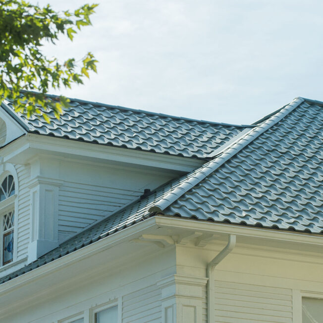 {Closeup view of a home with ProVia's new metal barrel tile roof in Jade, example of metal roofing that looks like clay tile}