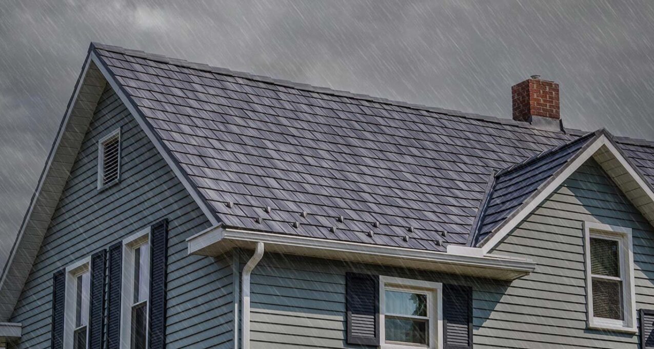 {Photo of a house in the rain showing a detailed ProVia Baystone Slate metal durable roofing system}