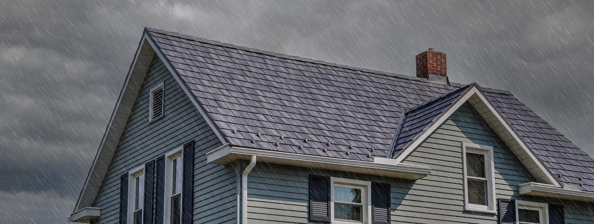 Photo of a house in the rain showing a detailed ProVia Baystone Slate metal durable roofing system