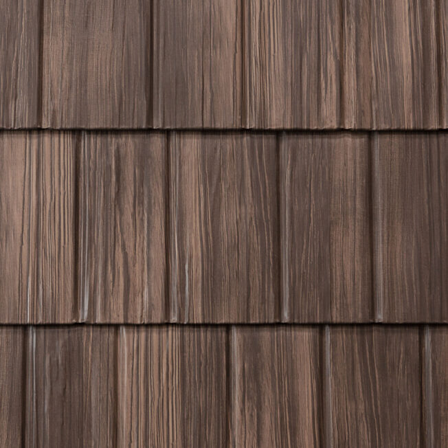 {Closeup image showing the details of ProVia's Saddlewood brown colored shake metal shingle roof, example of metal roofing that looks like shake}
