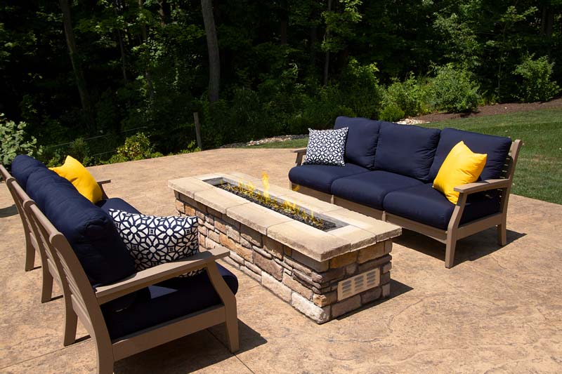 Stone fire pits and stone fire tables such as this one with two cozy outdoor sofas can be a great addition to outdoor spaces