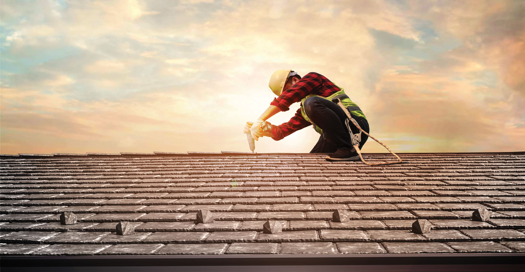 Roofing installer on a roof at sunrise installing ProVia slate metal roofing