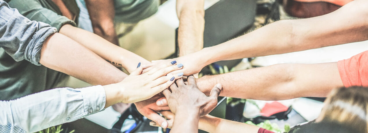 {Stock image of team member hands overlapping, representing team work or collaboration}