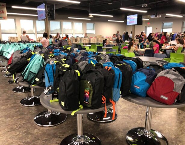 {Free backpacks stuffed with school supplies line the lunchroom at ProVia at annual Prepare for Success event}